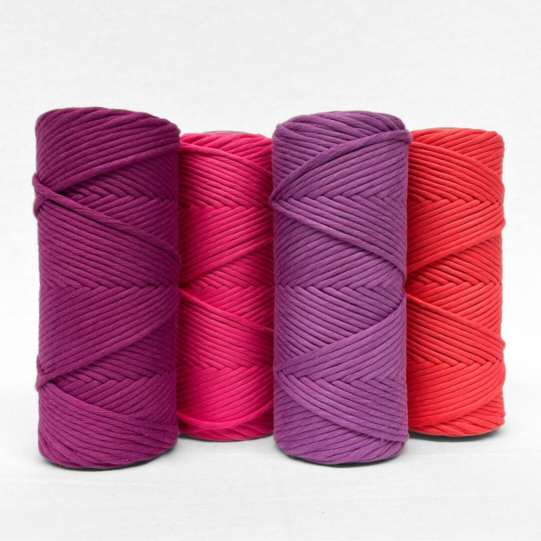 single rolls of cloud 9 luxe macrame cord in colur rich orchid vibrant purple laying flat on white background