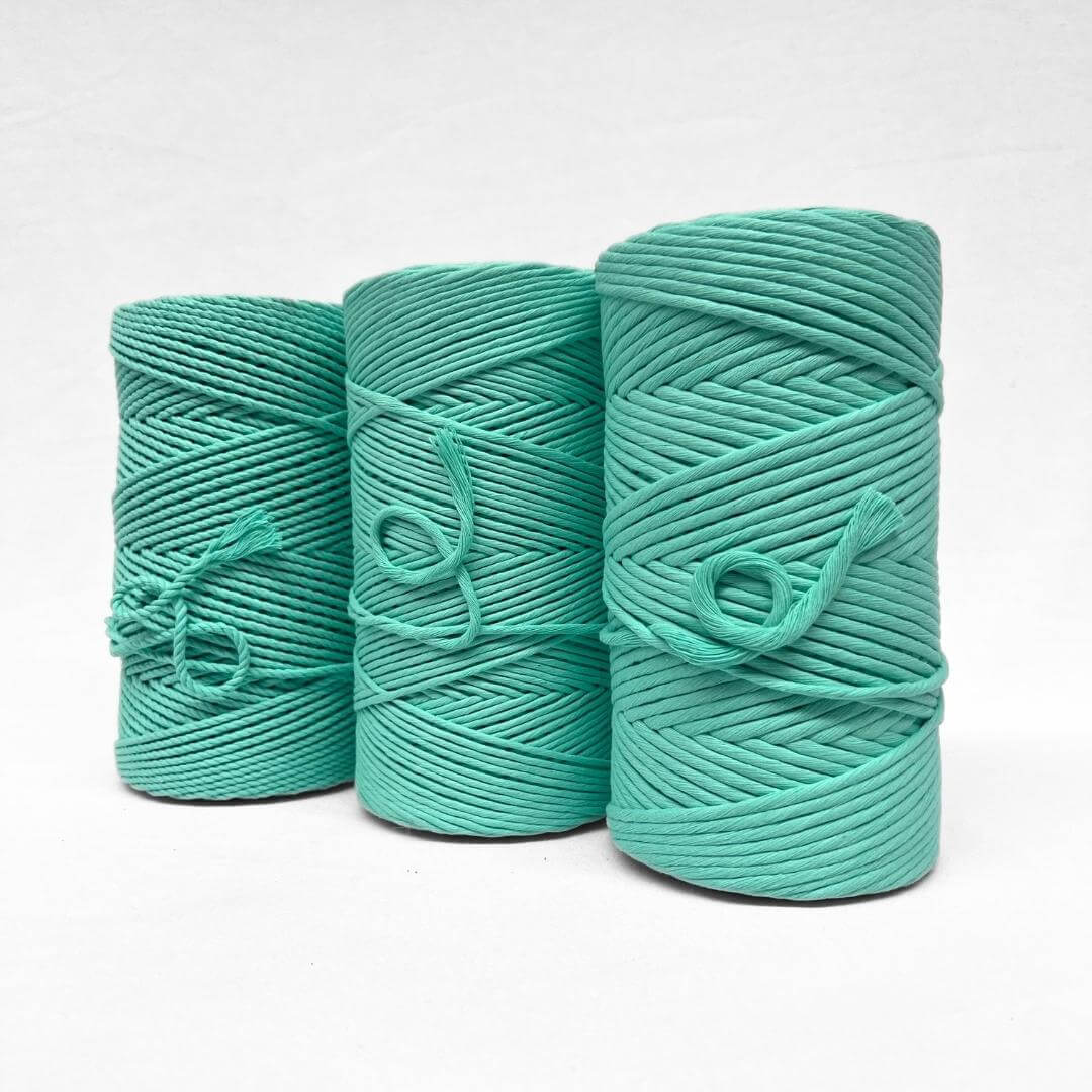 deep mint green 4mm rope cotton cord standing upright on whtie background showcasing product softness with small brushed out piece 