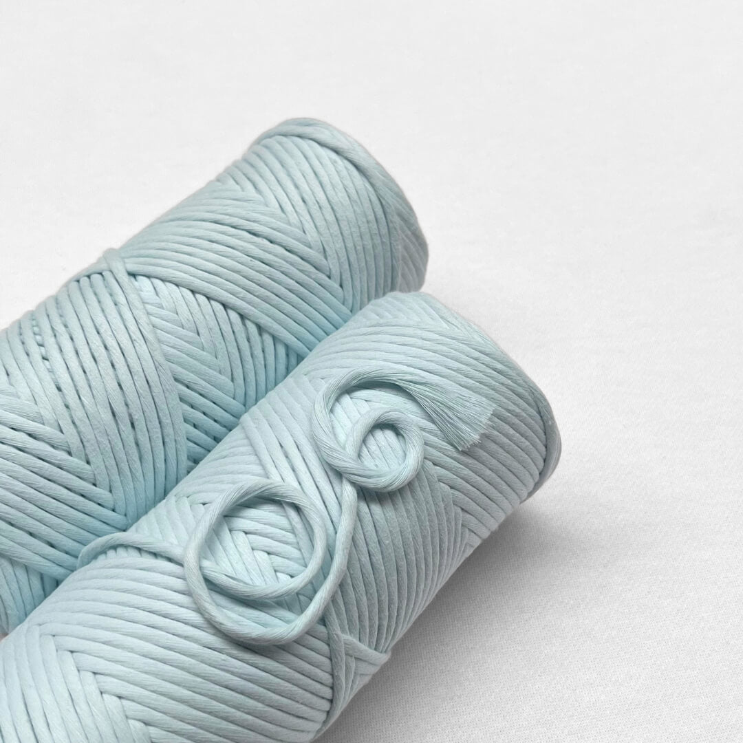 two rolls of pastel blue macrame string on white background 