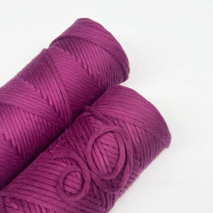 two rolls of rich orchid cotton cord for weaving and macrame laying flat on white background
