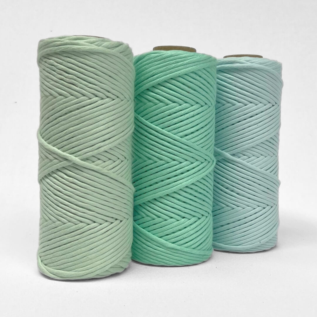 three rolls of 4mm cotton string in mint, spring green and blue frost standing side by side on white background 