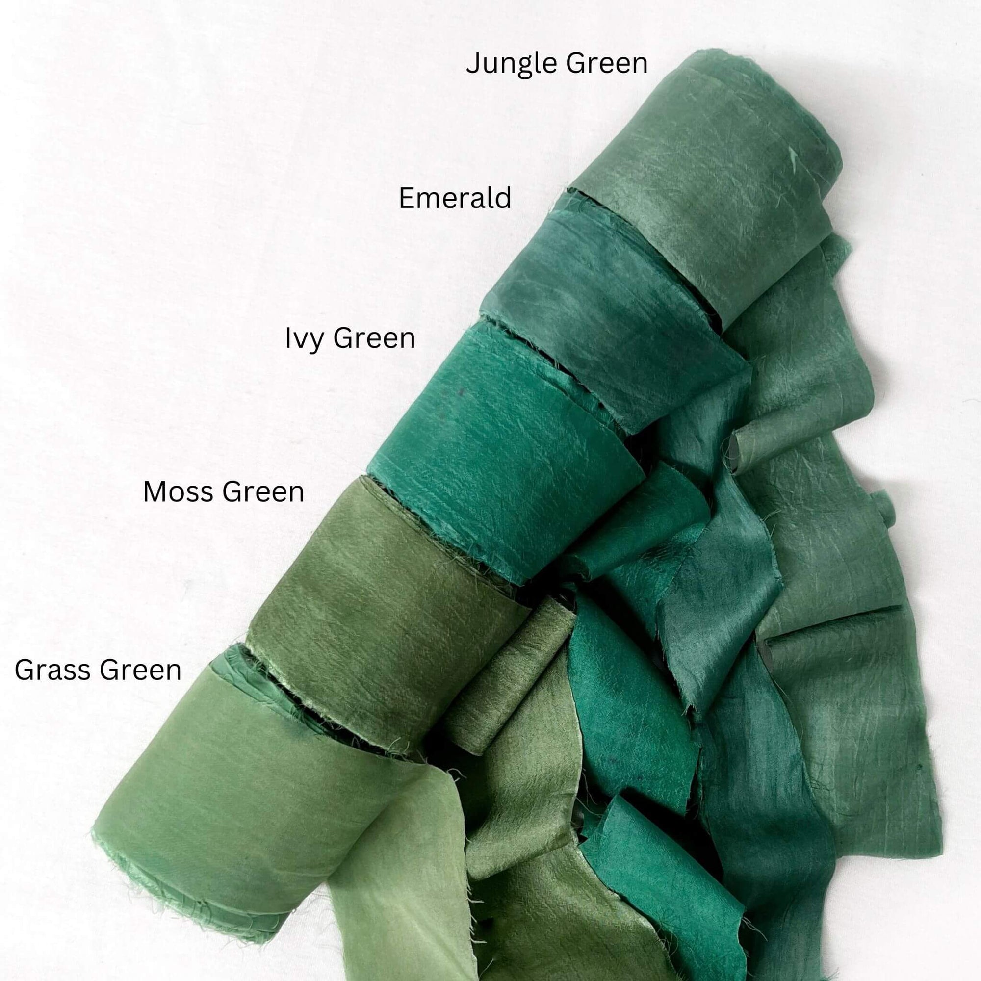 deep green tones jungle emerald ivy green moss grass silk roll group photo showing up close texture on white backdrop