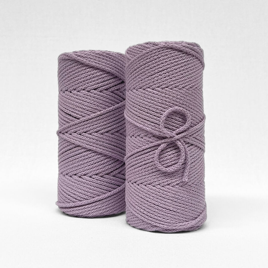 two rolls of orchid purple braided macrame cord standing side by side on white backdrop