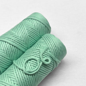two rolls of spring green macrame cord laying flat on white background