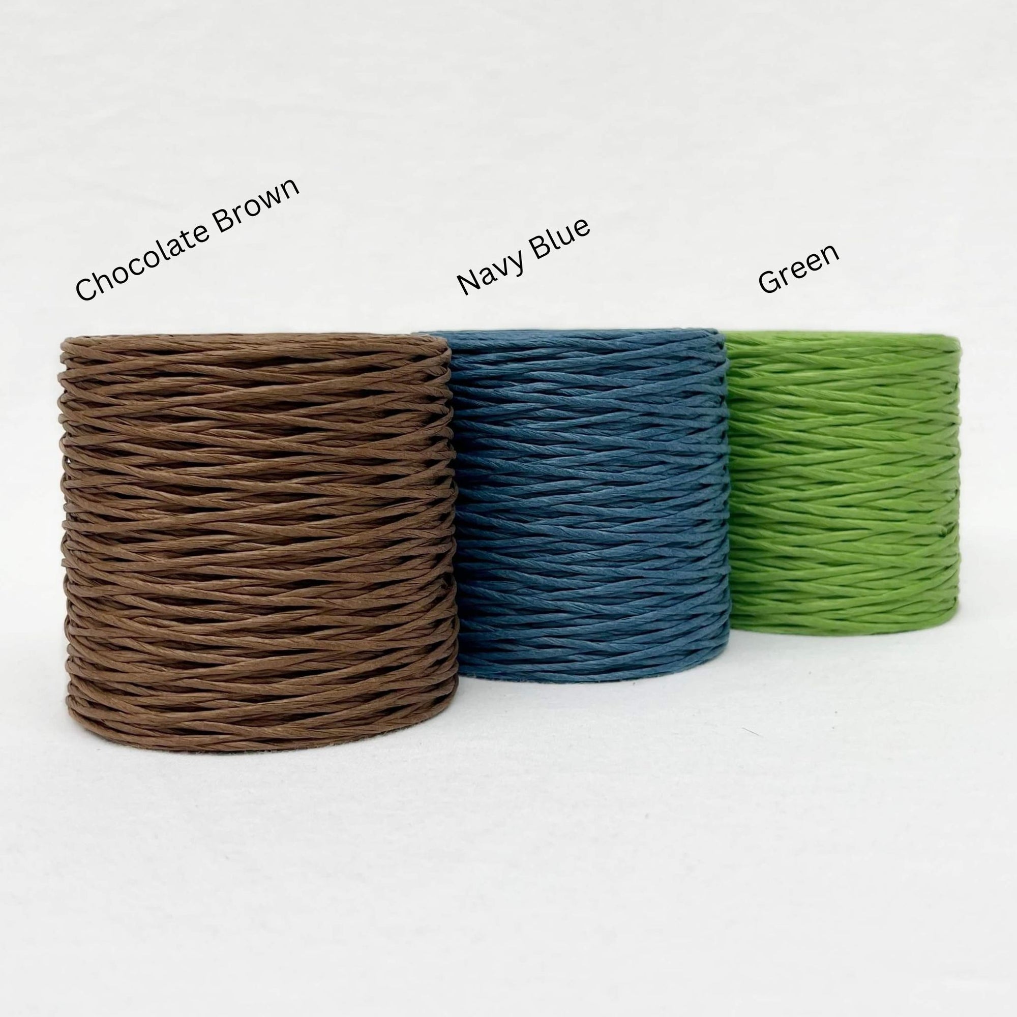 three rolls of paper twine in brown blue and green in group photo white wall