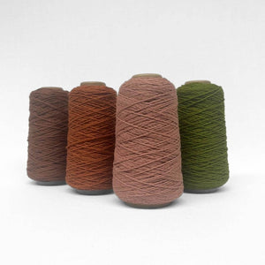 four rolls of wool cord in rose tea olive brown sugar and rust brown standing upright on white background showing complementing colours