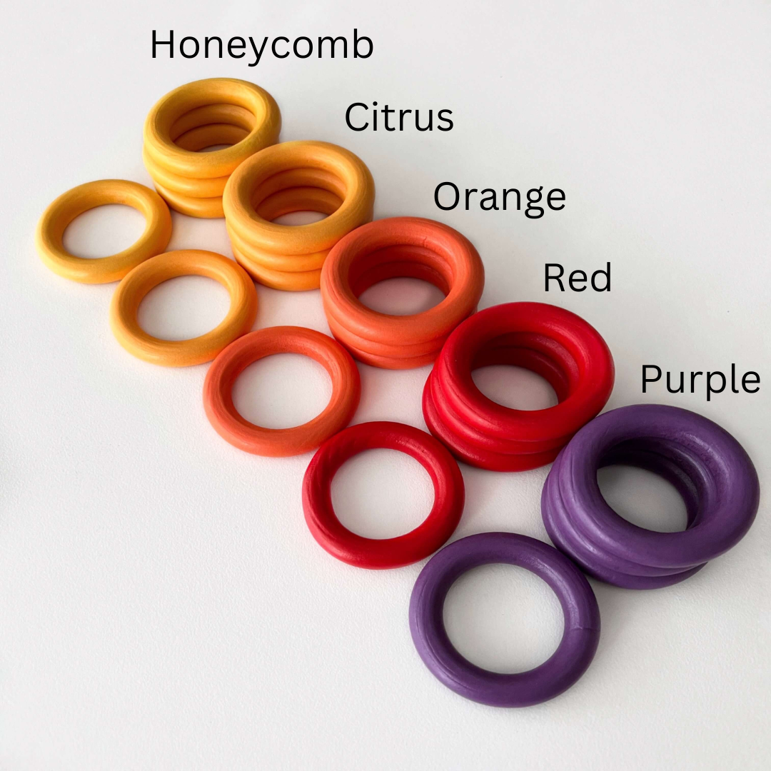 orange red and purple colourful wooden baby play rings in flatlay