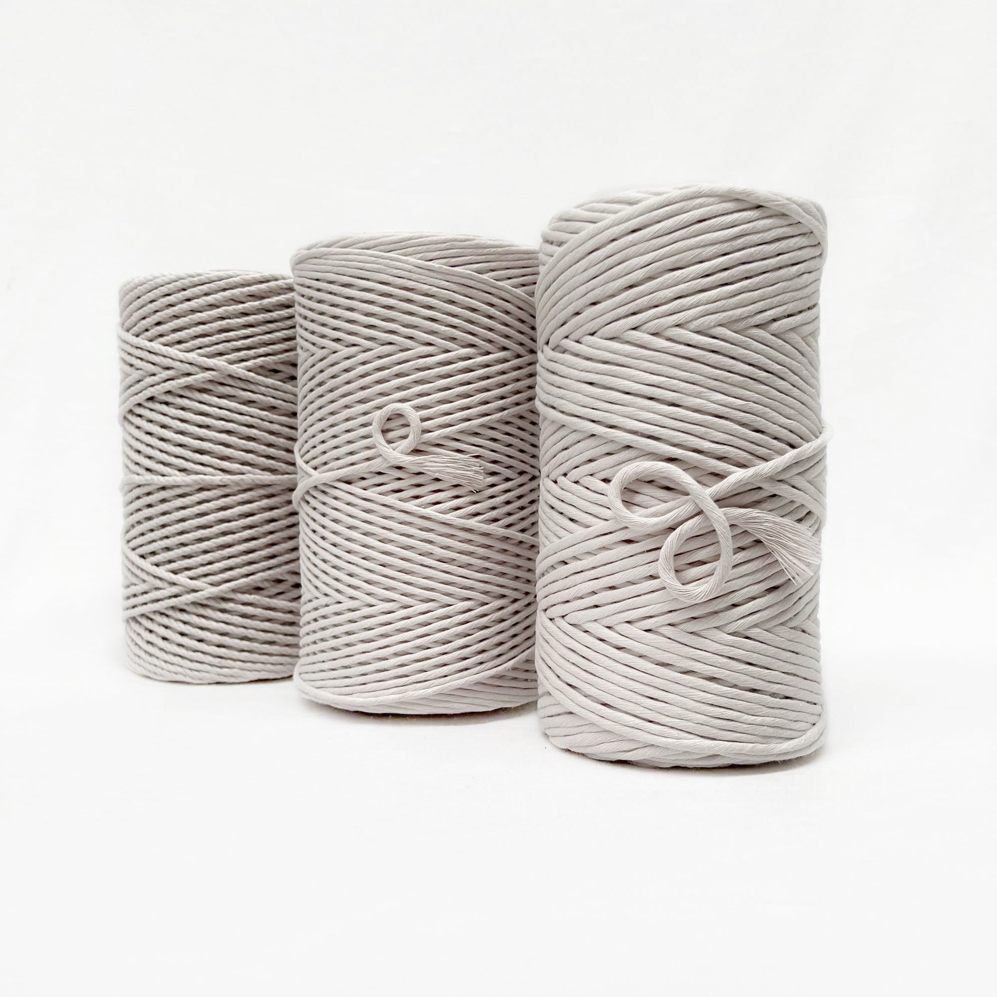 three sizes of ivory macrame cord standing in a line
