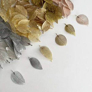 several figigree leaves lined up in a row to show difference from gold to silver