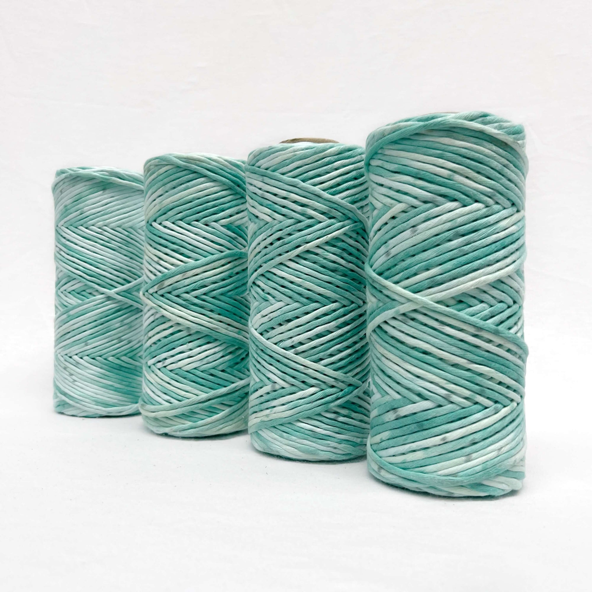 green macrame rope standing in line of four with white background