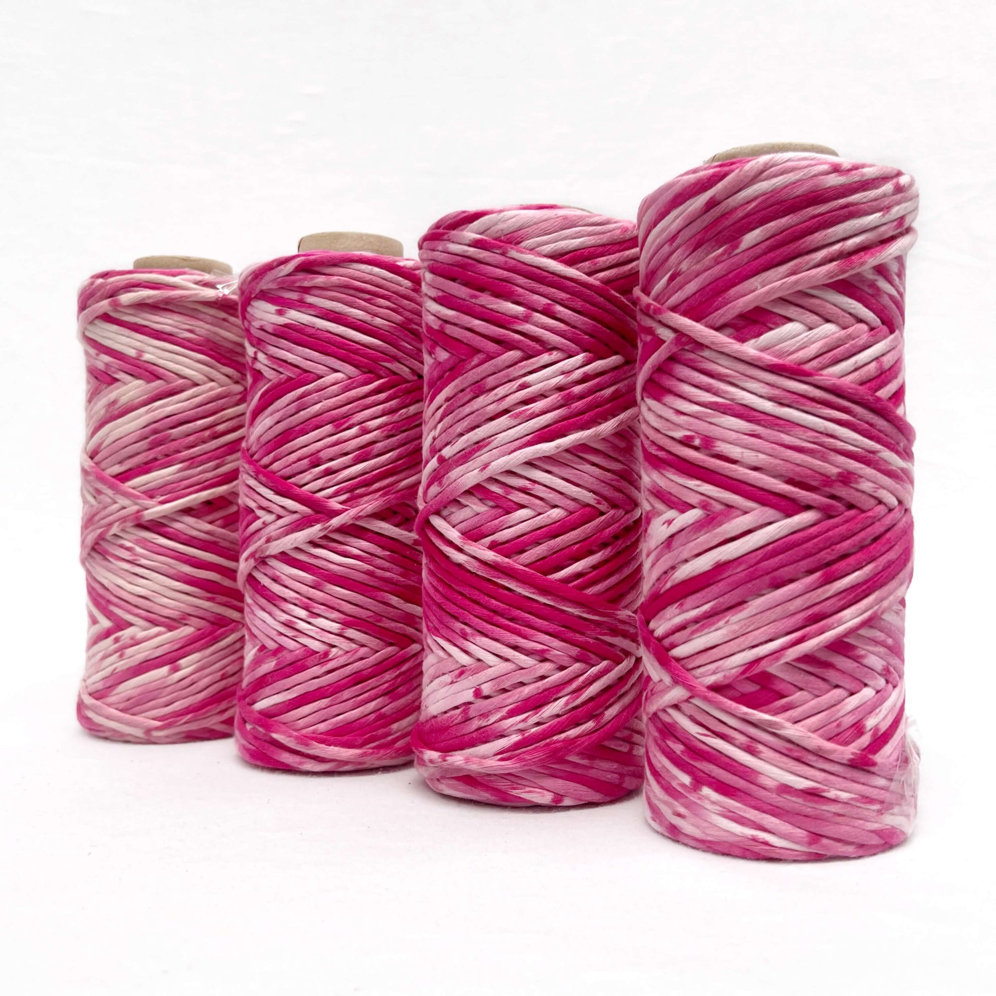 bright pink macrame cord standing in line against white wall