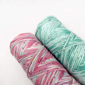 macrame craft cord in green and pink laying flat on white surface